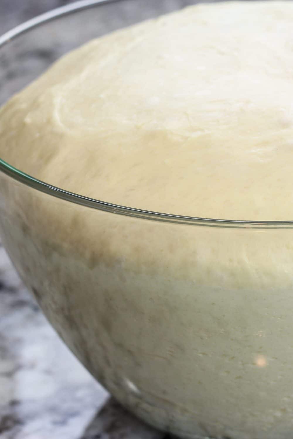 Raw Danish dough in a glass bowl doubled in size after it rose. 