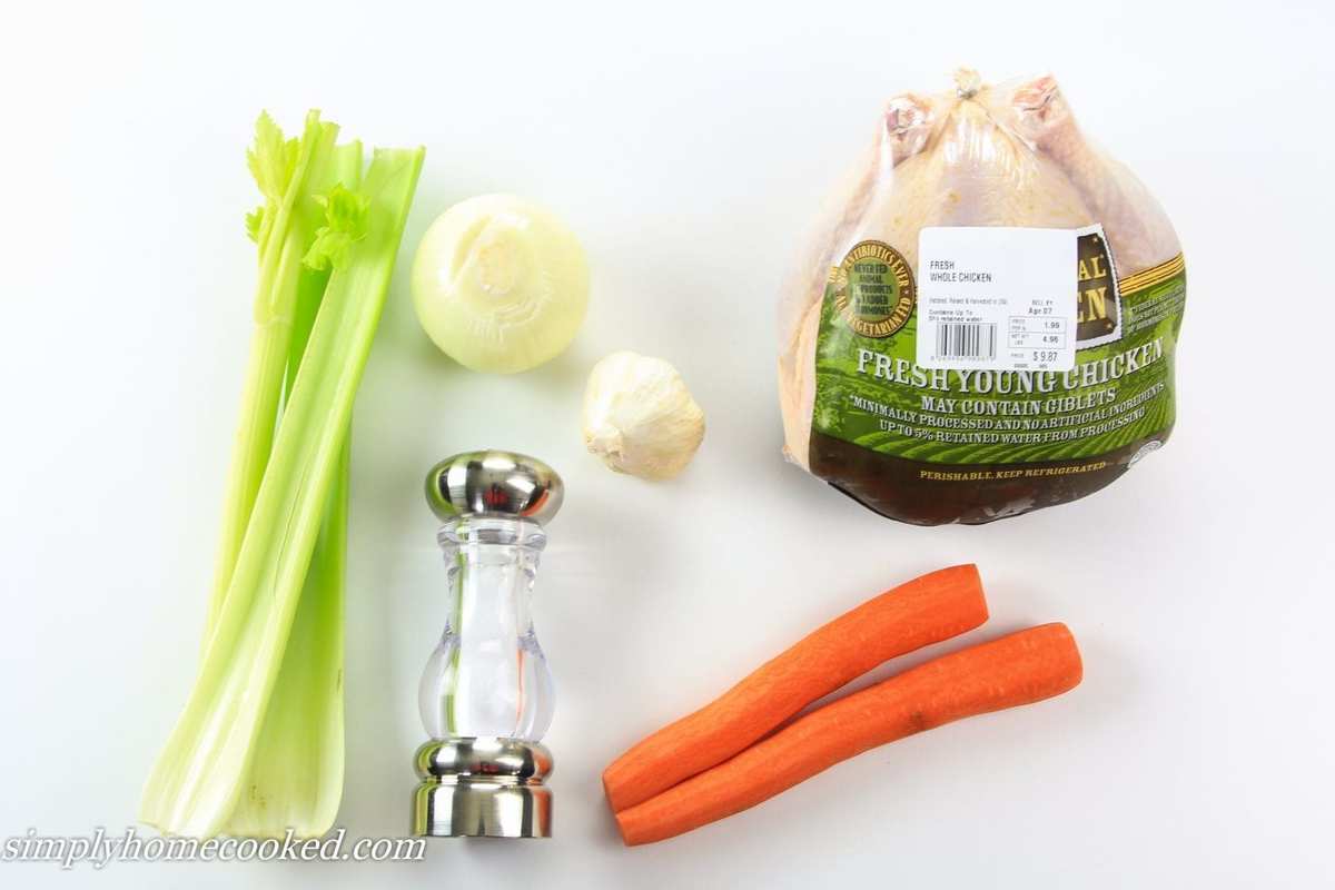 an overhead image of ingredients for chicken broth in a white background