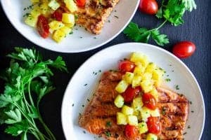 salmon fillets with pineapple and cherry tomatoes on the salmon.