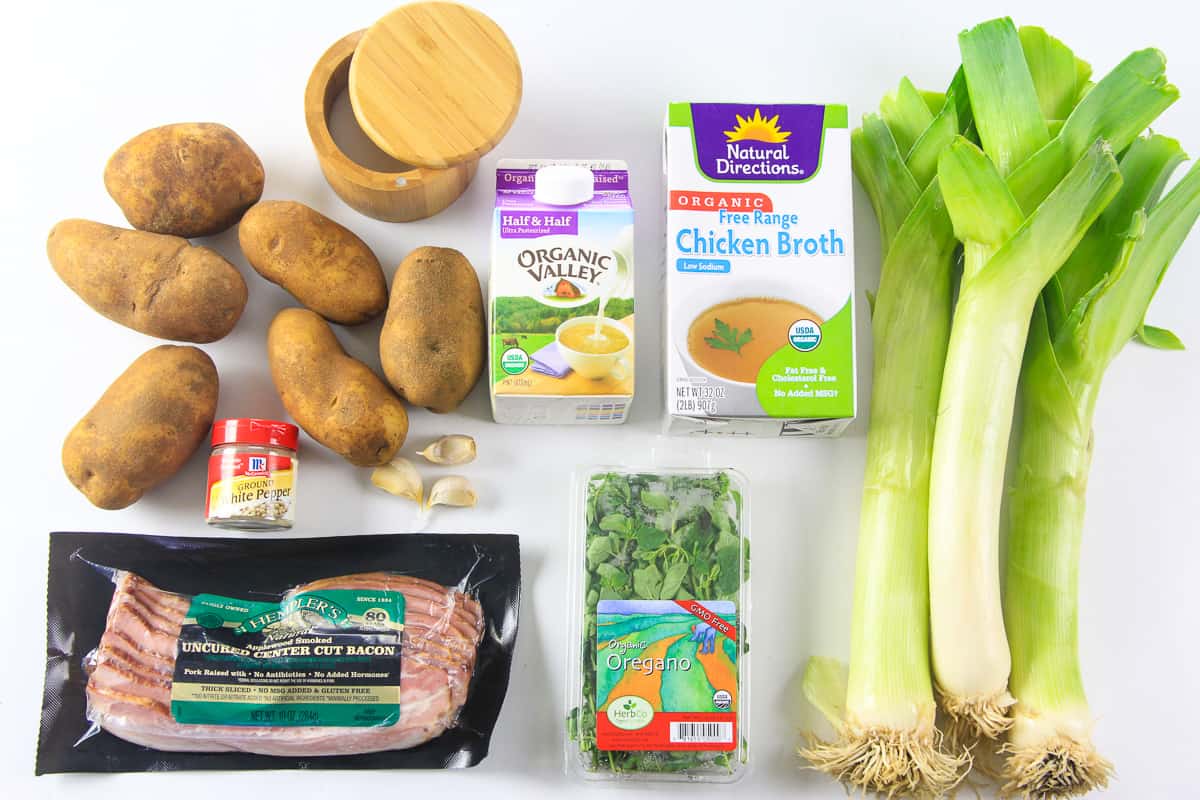 This Creamy Potato Soup with Leeks and Bacon is a delicious meal that combines simple flavors to create a meal that everyone loves! #creamysoup #potatosoup #potatoleeksoup #leeksoup #souprecipe Ingredients for creamy potato soup laying on a flat white surface and photographed from overhead