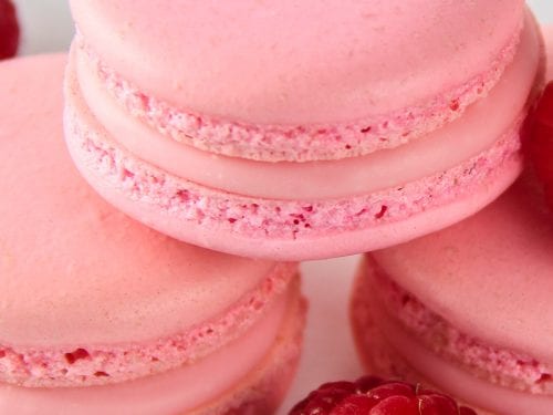 Making homemade French Macarons with raspberry coffee flavor: light pink,  unbaked macaron batter, so called macaronage, piped in circles on white parchment  paper before baking Stock Photo