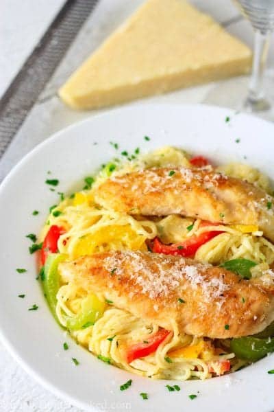 pan fried chicken tenders, pasta, and sautéed peppers in a white plate