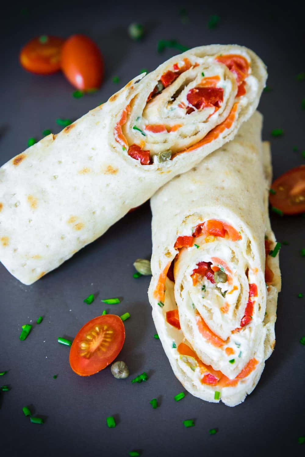 sliced smoked salmon wrap with cherry tomatoes and chopped chives next to it