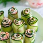 smoked salmon spread rolled inside of thinly sliced cucumbers on a white plate