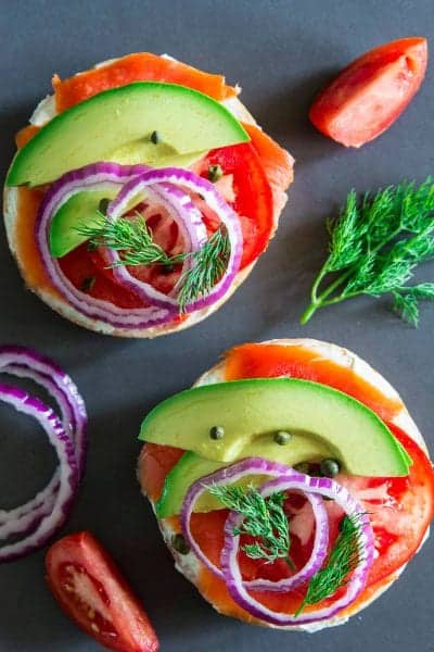 smoked salmon bagel with cream cheese, avocado, tomato, capers, and red onion