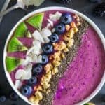 blueberry smoothie bowl with chopped kiwi, coconut flakes, granola, and chia seeds on top