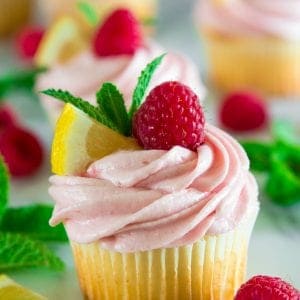 lemon cupcakes with raspberry buttercream topped with raspberries, sliced lemon, and mint