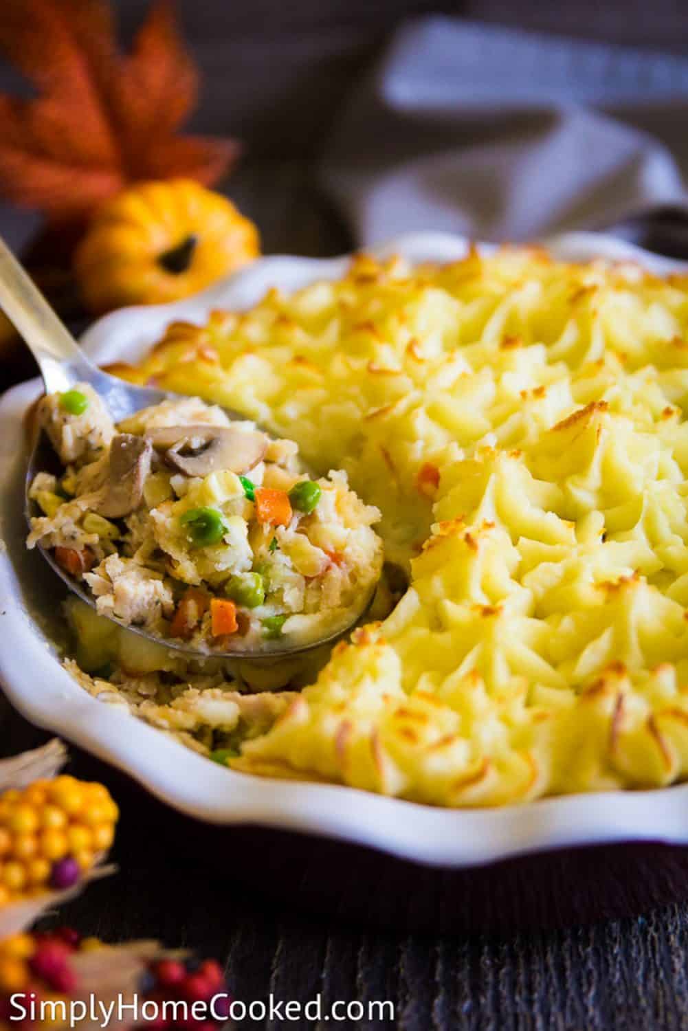 a close up image of a shepherds pie with a filling made out of thanksgiving leftovers including peas, carrots, and corn