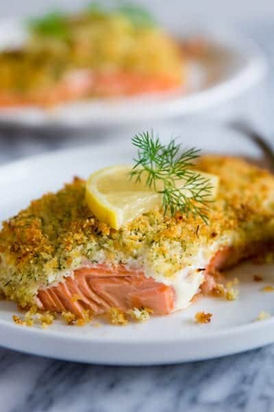 panko crusted salmon with a slice of lemon on a white plate with fresh dill on top.
