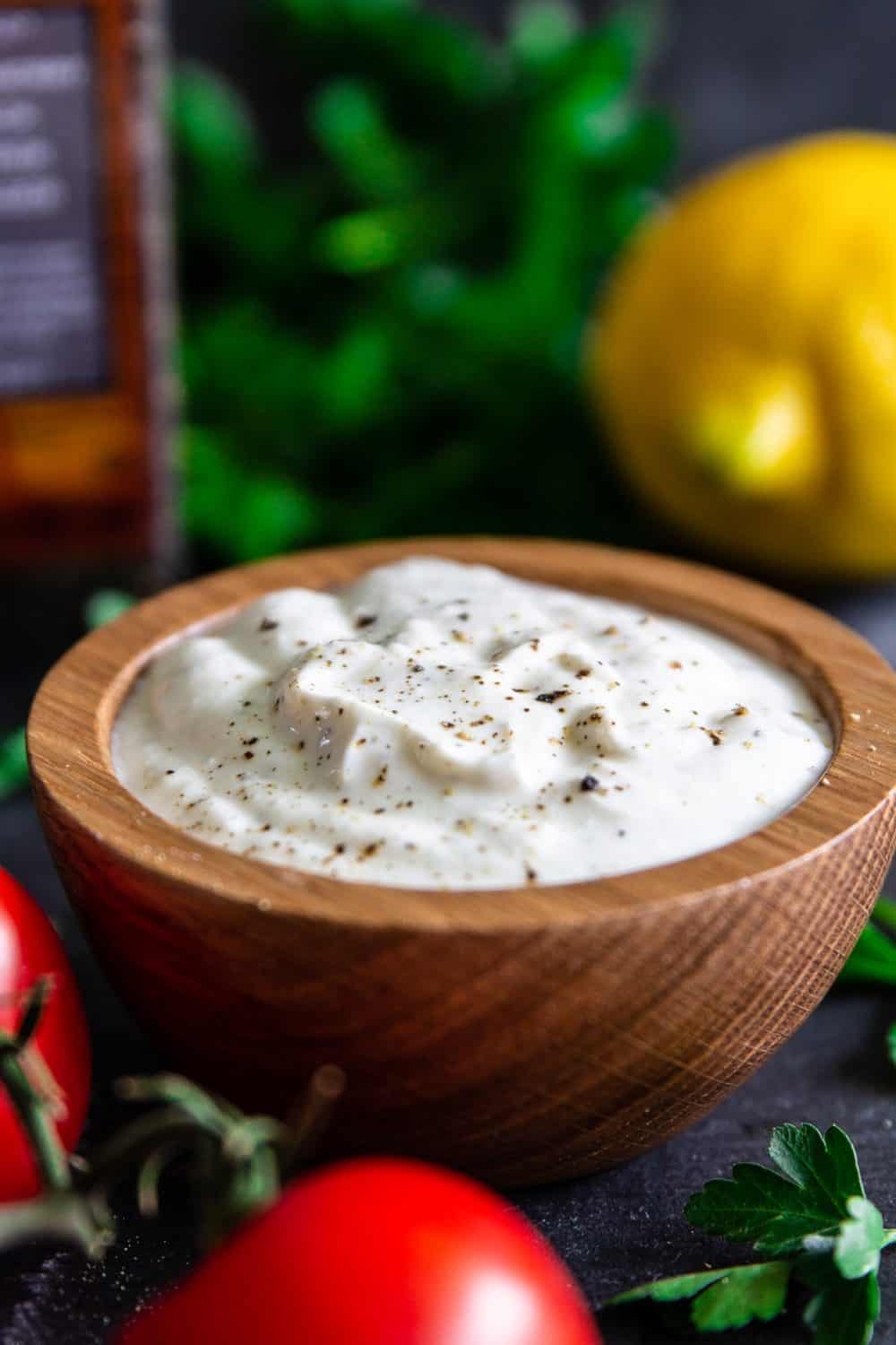 Creamy Greek Yogurt sauce with pepper sprinkled on top and a lemon in the background