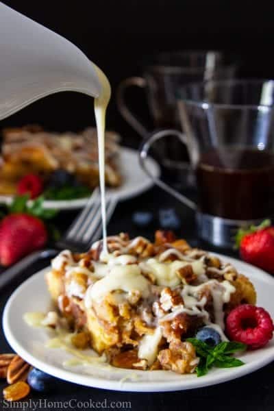 sliced bread pudding with vanilla rum sauce on top and berries beside it