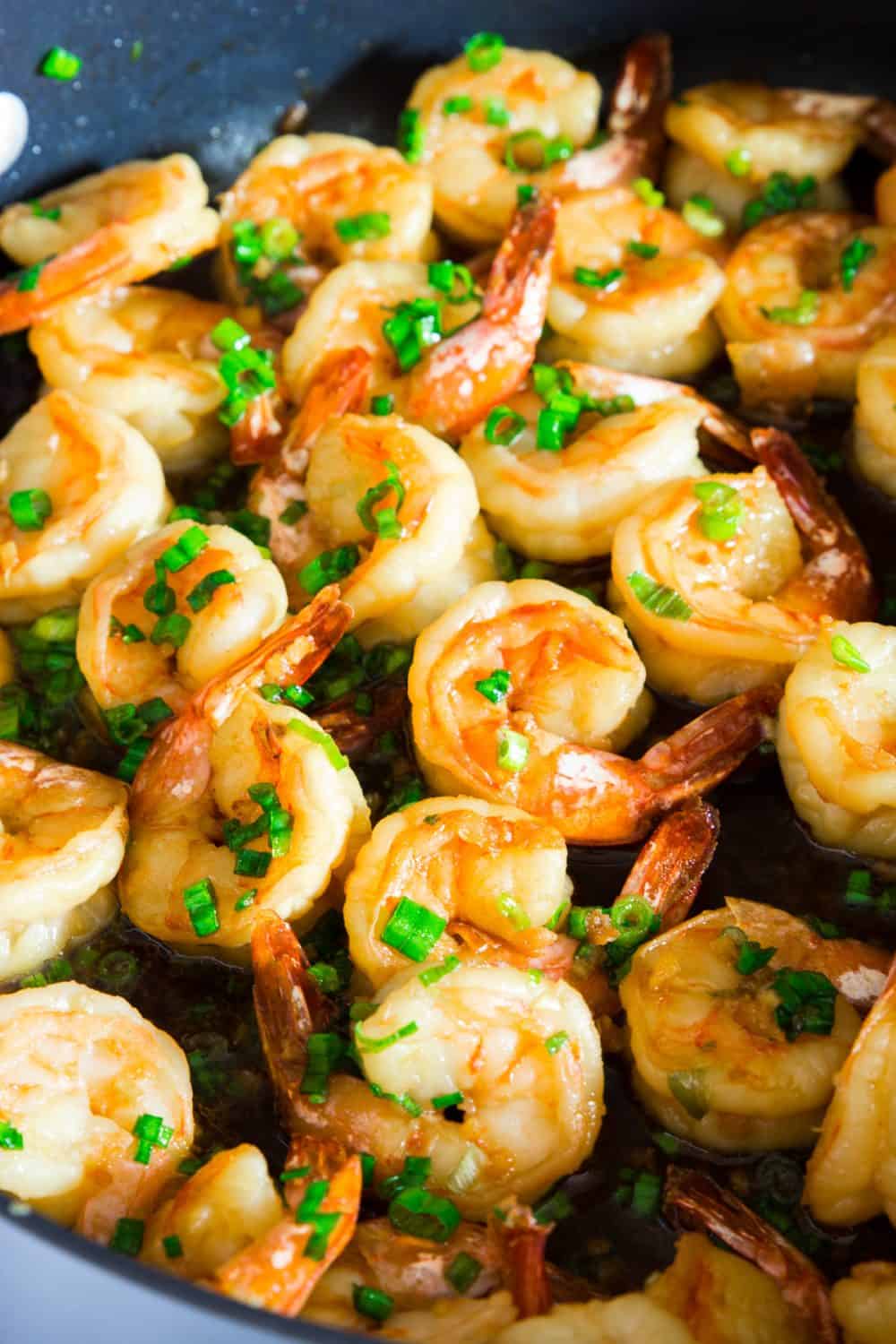 garlic ginger shrimp with sliced green onion and sesame seeds on top.