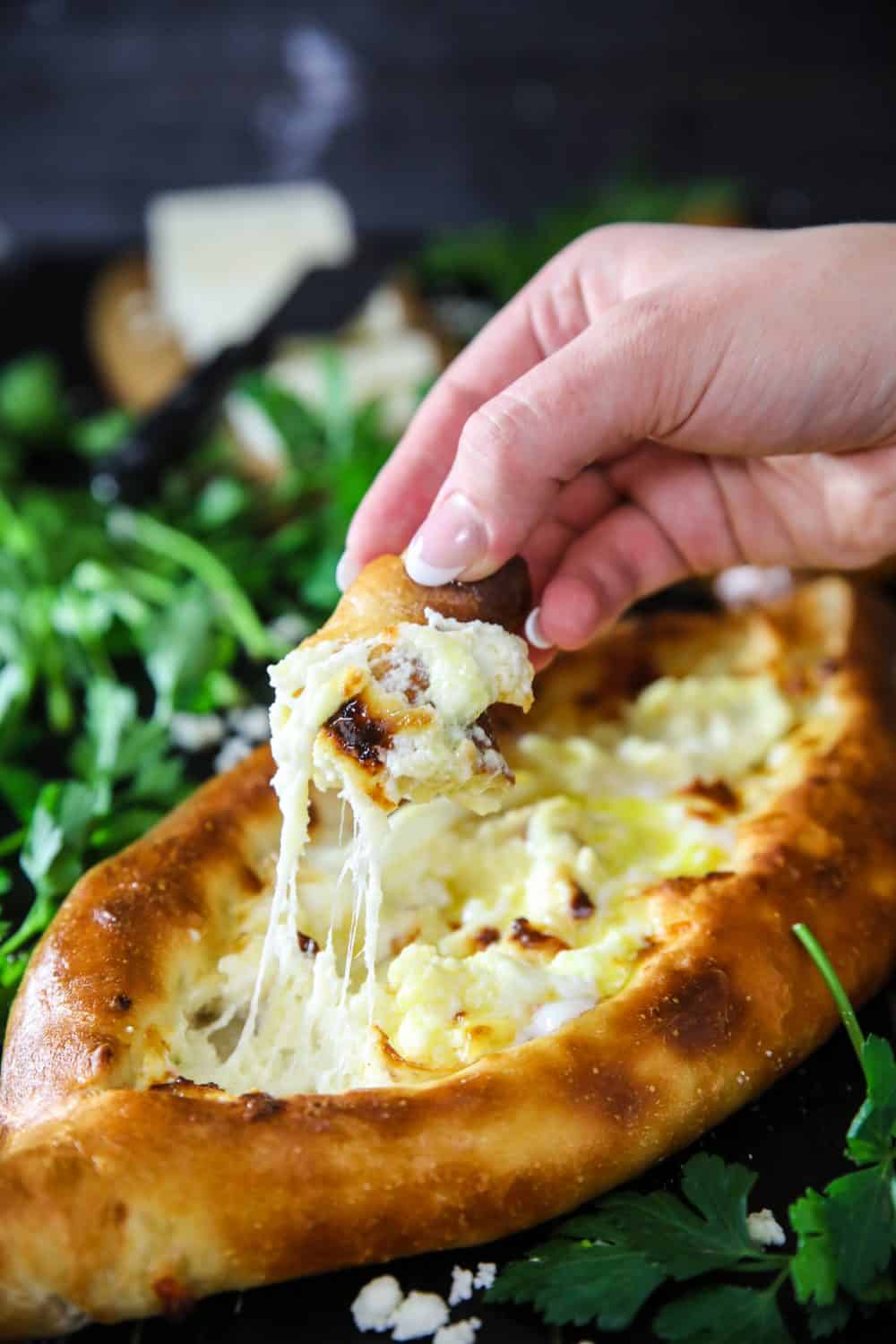 dipping bread into melted cheese from easy georgian khachapuri