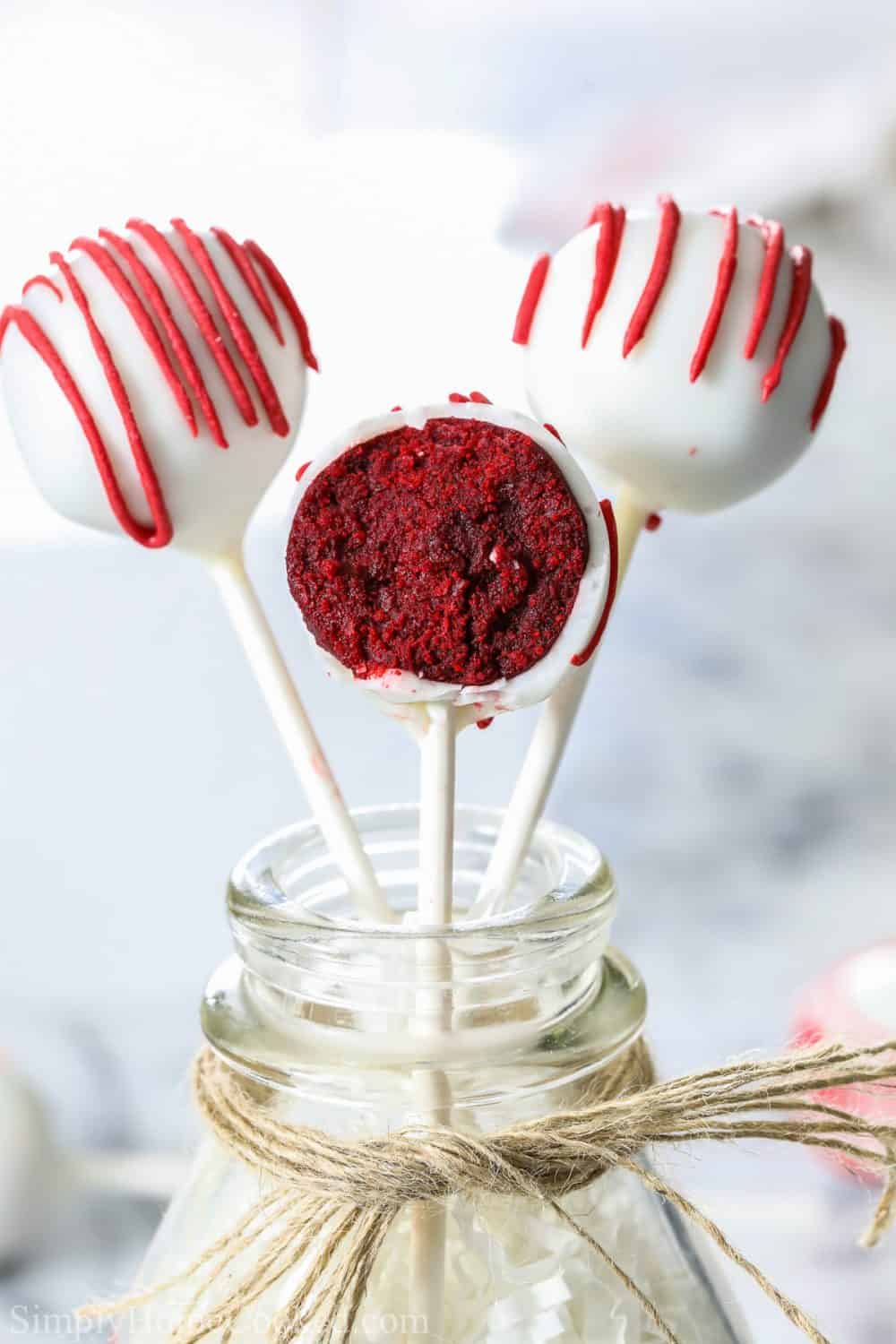 3 red velvet cake pops covered in white candy melts and drizzled with red candy melts