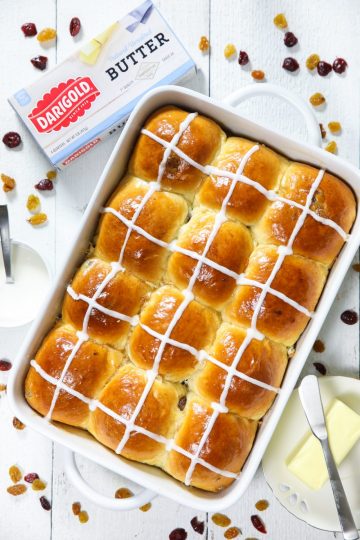 Warm fluffy and butter brioche hot cross buns in a white baking dish ready to eat