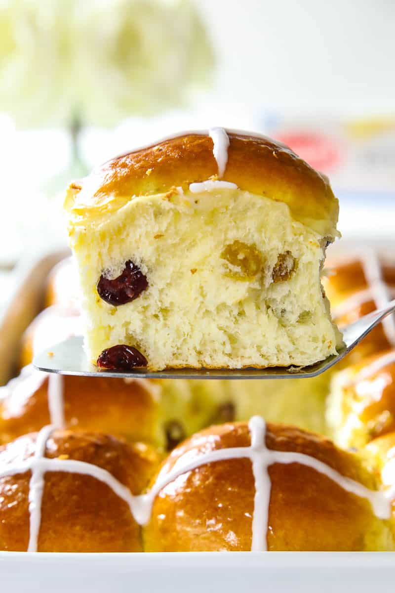 close up image of a hot cross bun held on a serving spatula