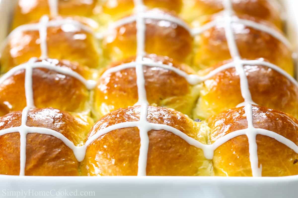 close up image of brioche hot cross buns in a white baking dish