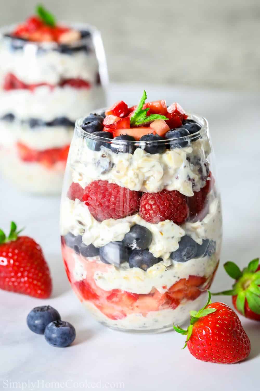 greek yogurt and berry parfait in a wine glass with mint leaves on top as garnish