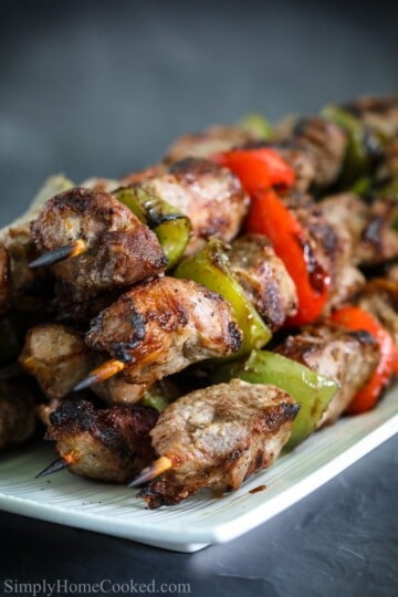 Close up photo of pork kabobs shashlik on a white narrow plate