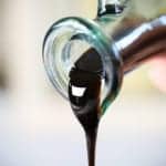 homemade balsamic glaze being poured out of a small glass oil dispenser