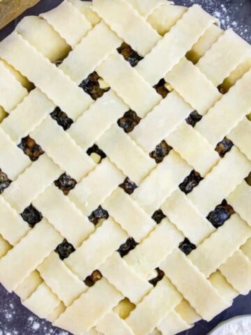 overhead image of homemade blueberry pie with a lattice pie crust on a slate background