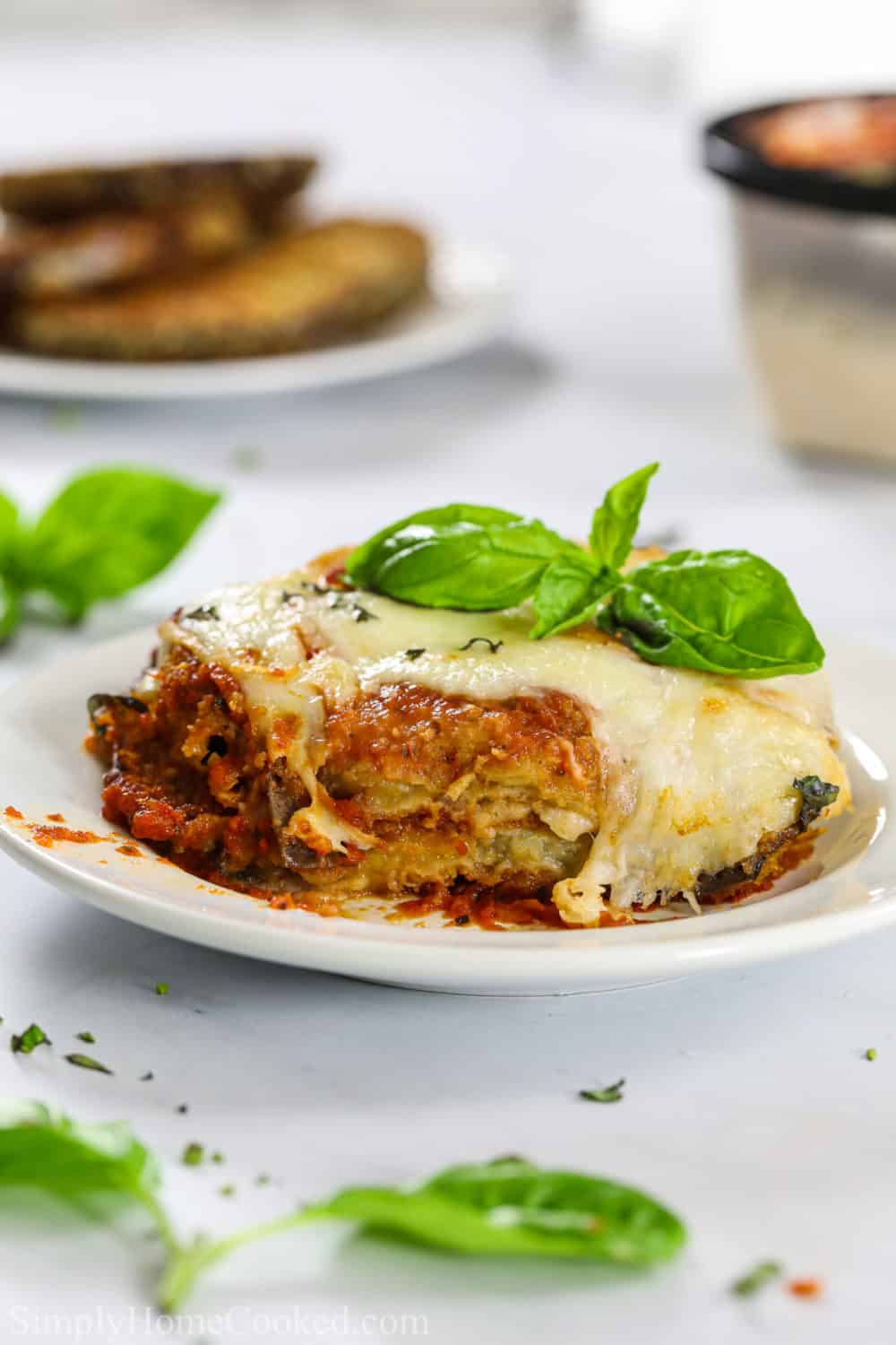 a piece of eggplant parmesan on a plate with some basil on top of the baked parmesan