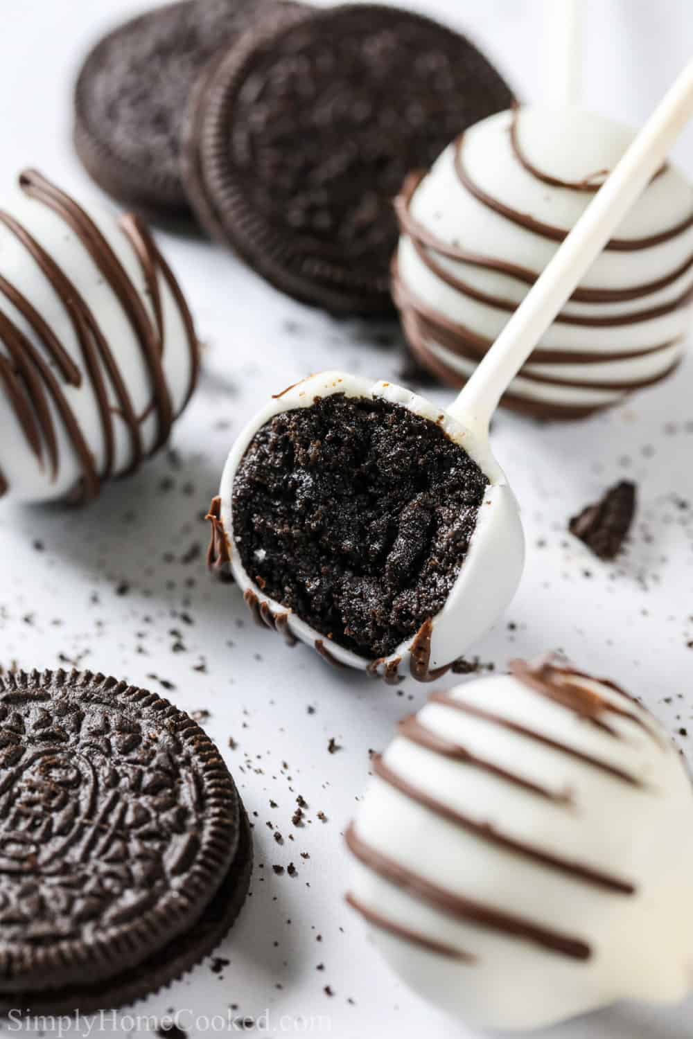 close up image of no bake Oreo cake pops on a white background with Oreo cookies beside the cake pops