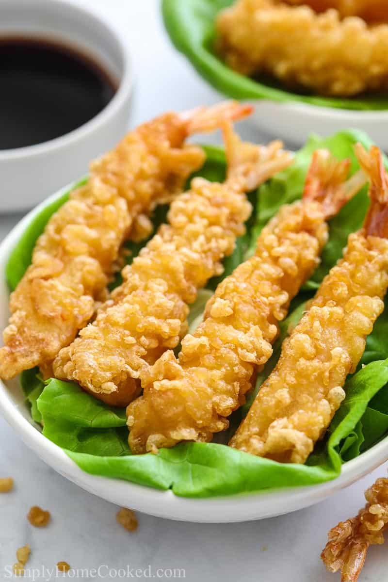 close up image of crispy fried shrimp tempura on a plate lined with butter lettuce leaves