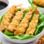 horizontal image of crispy fried shrimp tempura on a plate lined with butter lettuce leaves