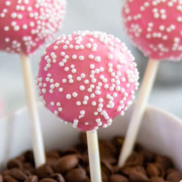 close up image of pink vanilla cake pops with white nonpareils on top