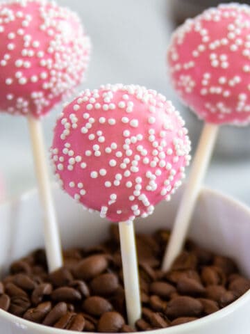 close up image of pink vanilla cake pops with white nonpareils on top