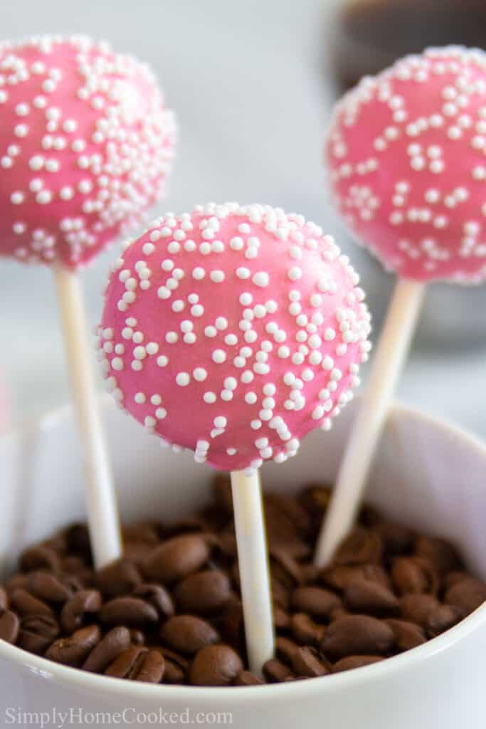 close up image of pink vanilla cake pops with white nonpareils on top 
