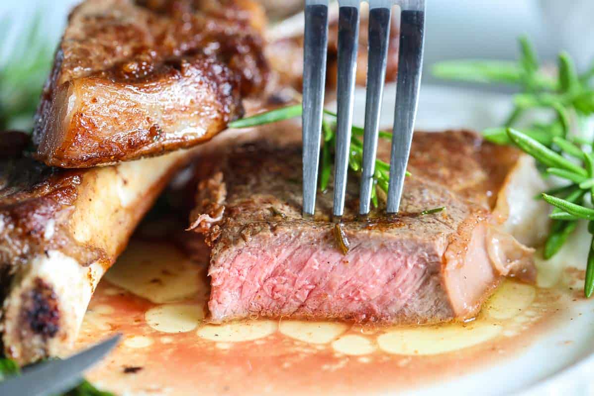close up image of sliced cooked steak with a fork piercing it