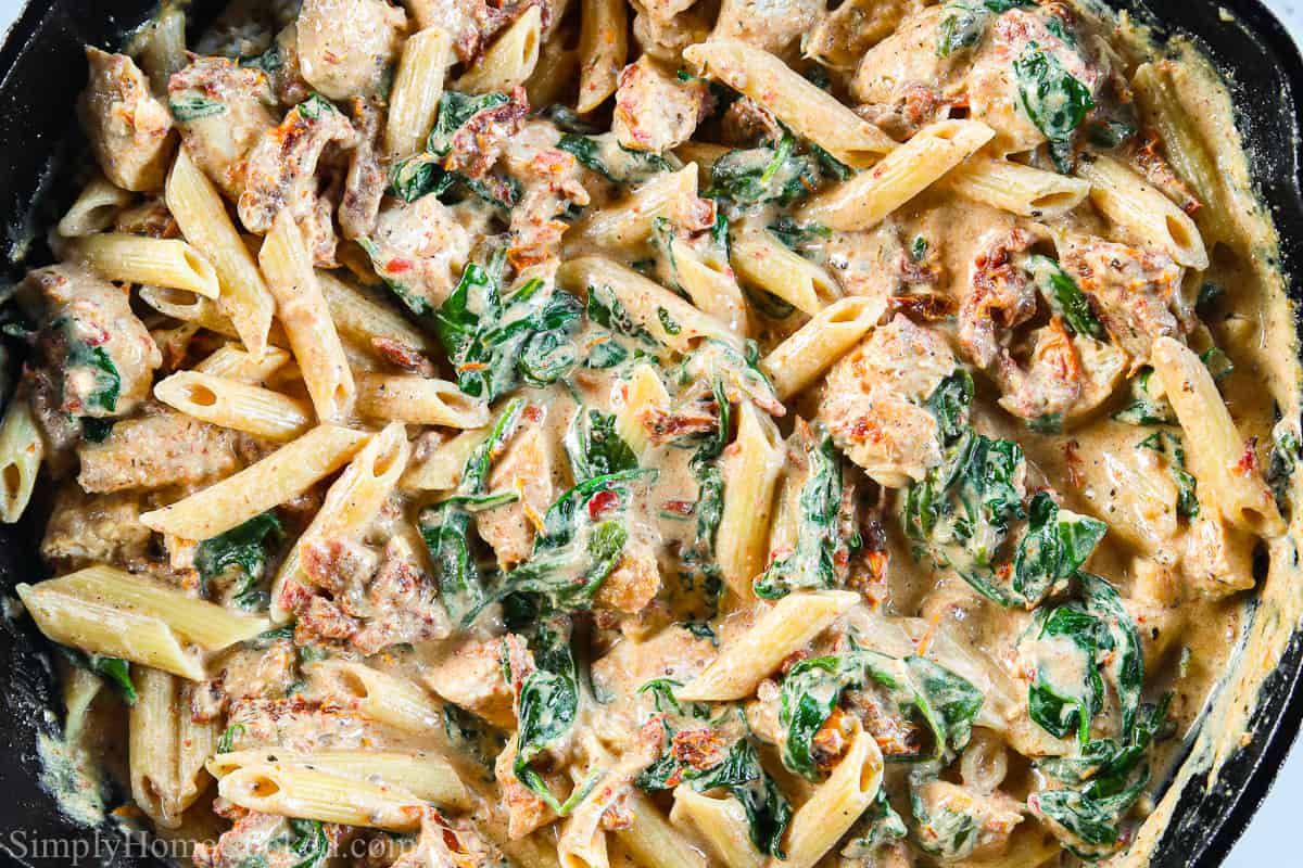 Close up of Creamy Tuscan Chicken Pasta in a cast iron skillet.
