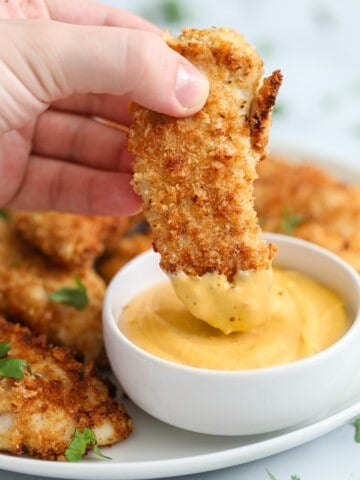 close up image of air fryer chicken tender being dipped in chick-fil-a sauce