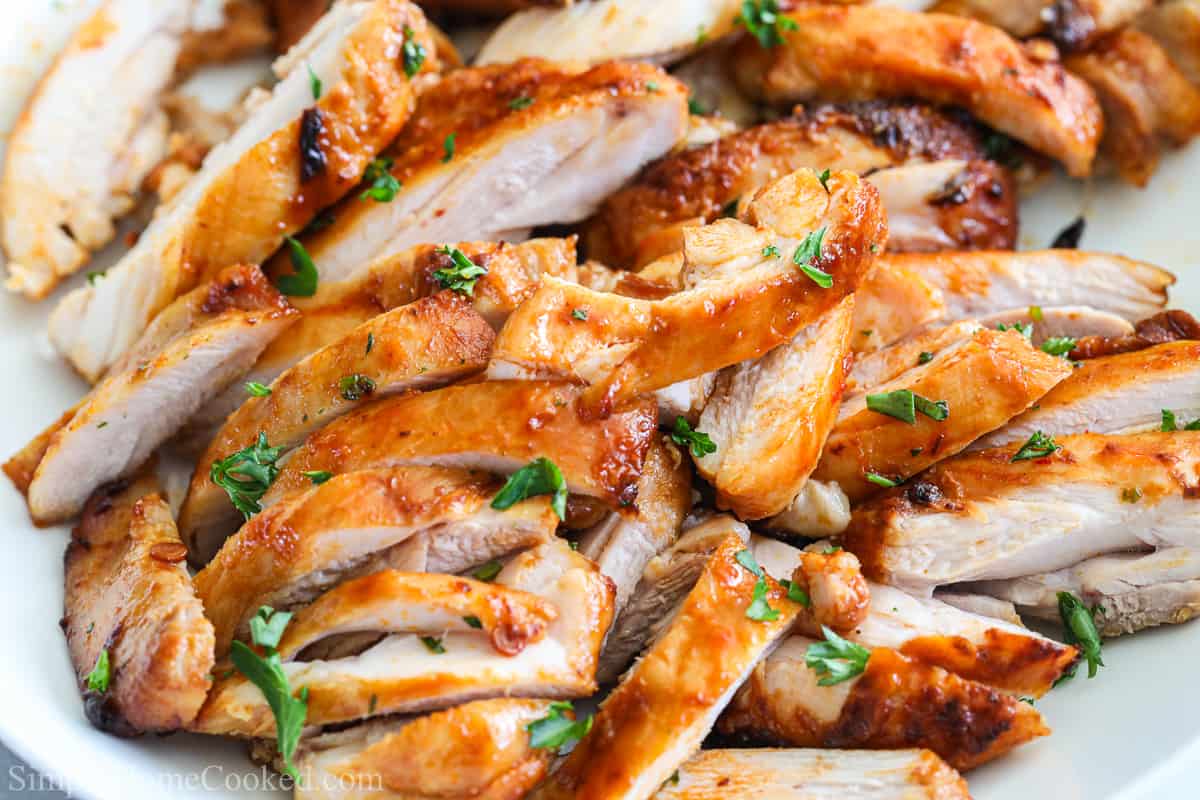 Close up of chipotle chicken thighs sliced into strips and garnished with parsley.