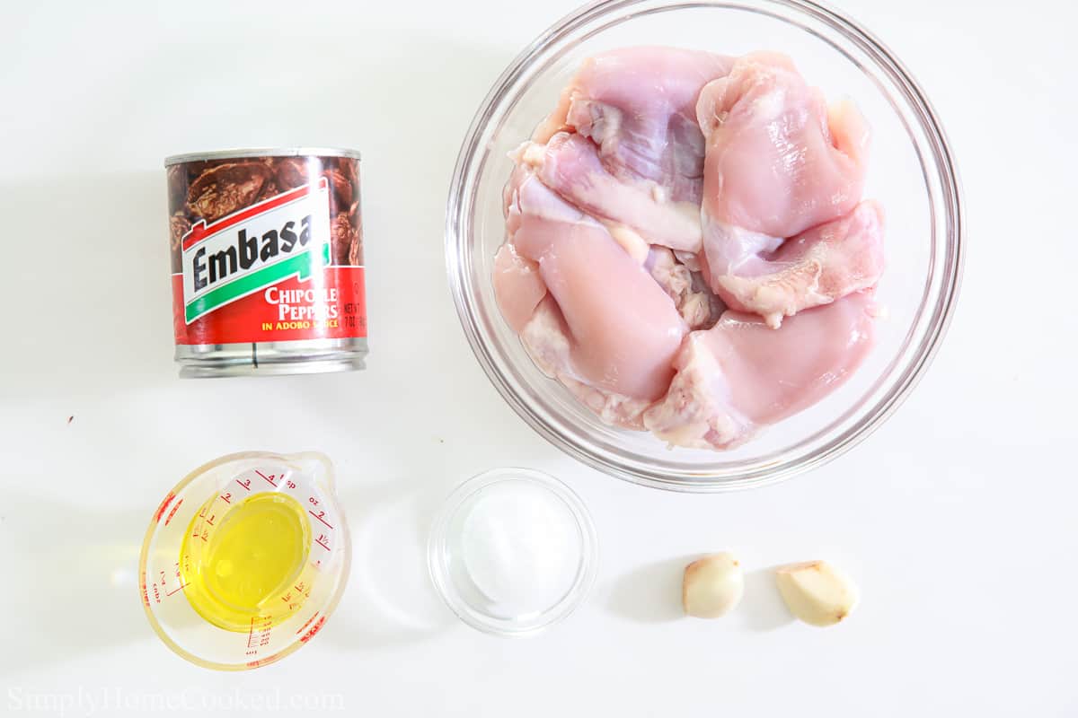 Ingredients for Air fryer Chipotle Chicken Thighs, including boneless skinless chicken thighs, chipotle peppers, oil, garlic cloves, and salt.