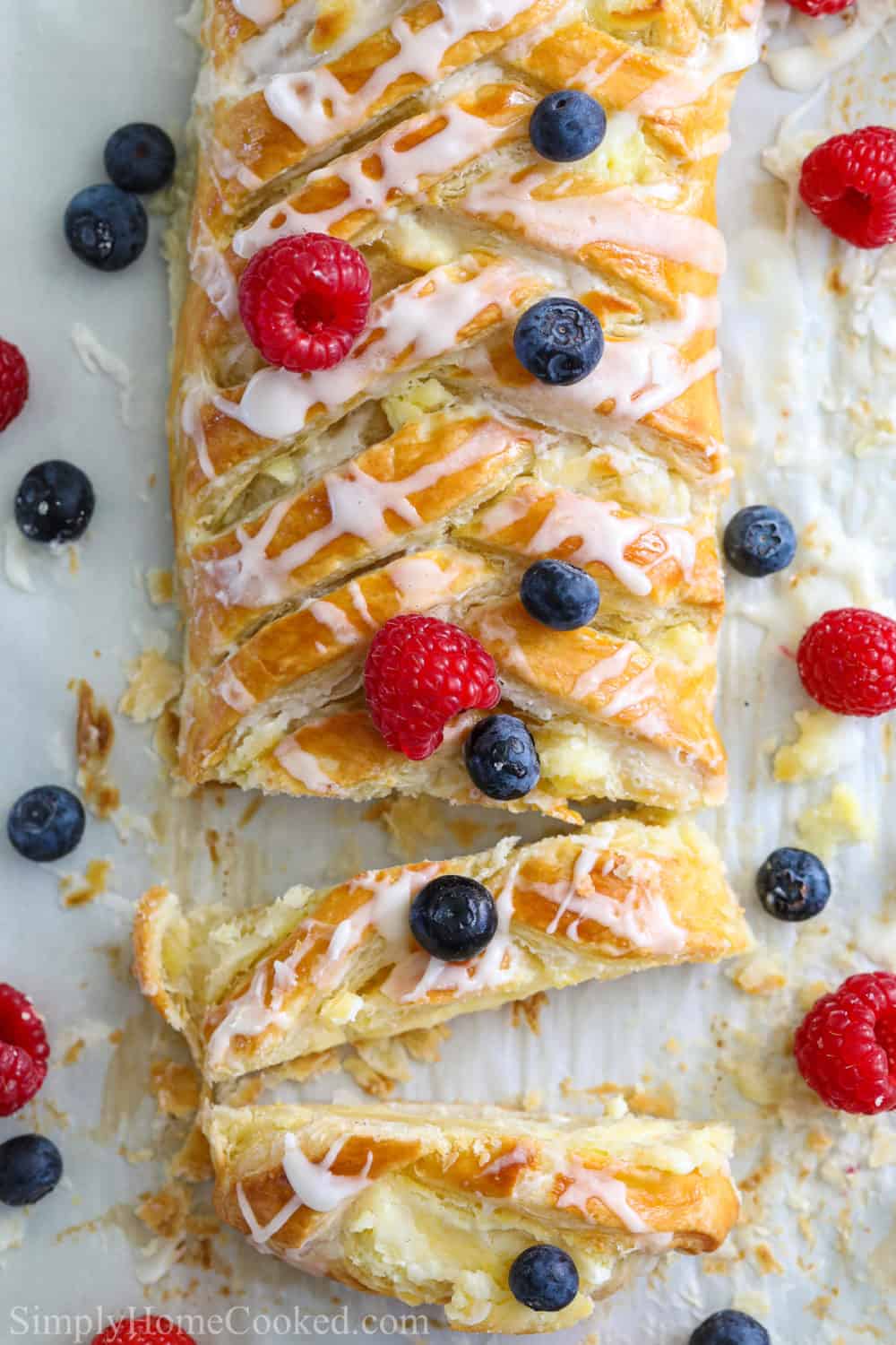 Easy Cheese Danish sliced and covered in berries on a white background.