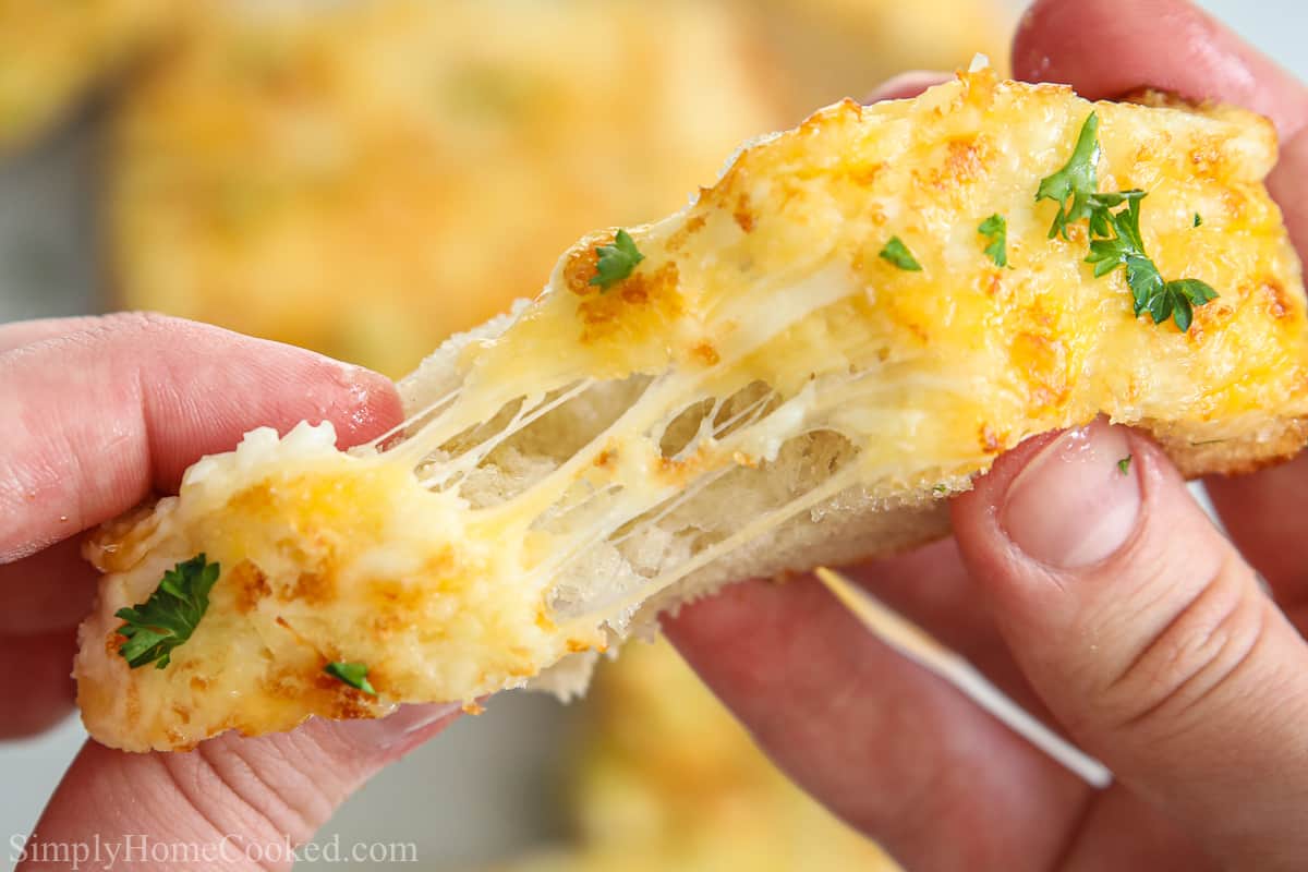 Slice of Garlic Cheese Bread pulled apart as the melted cheese stretches.