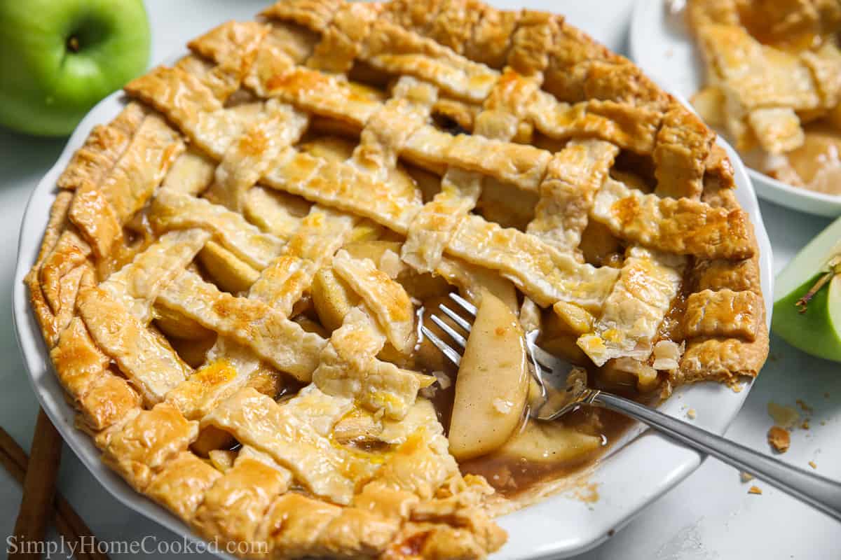 Homemade apple pie with a slice missing and a fork in it.