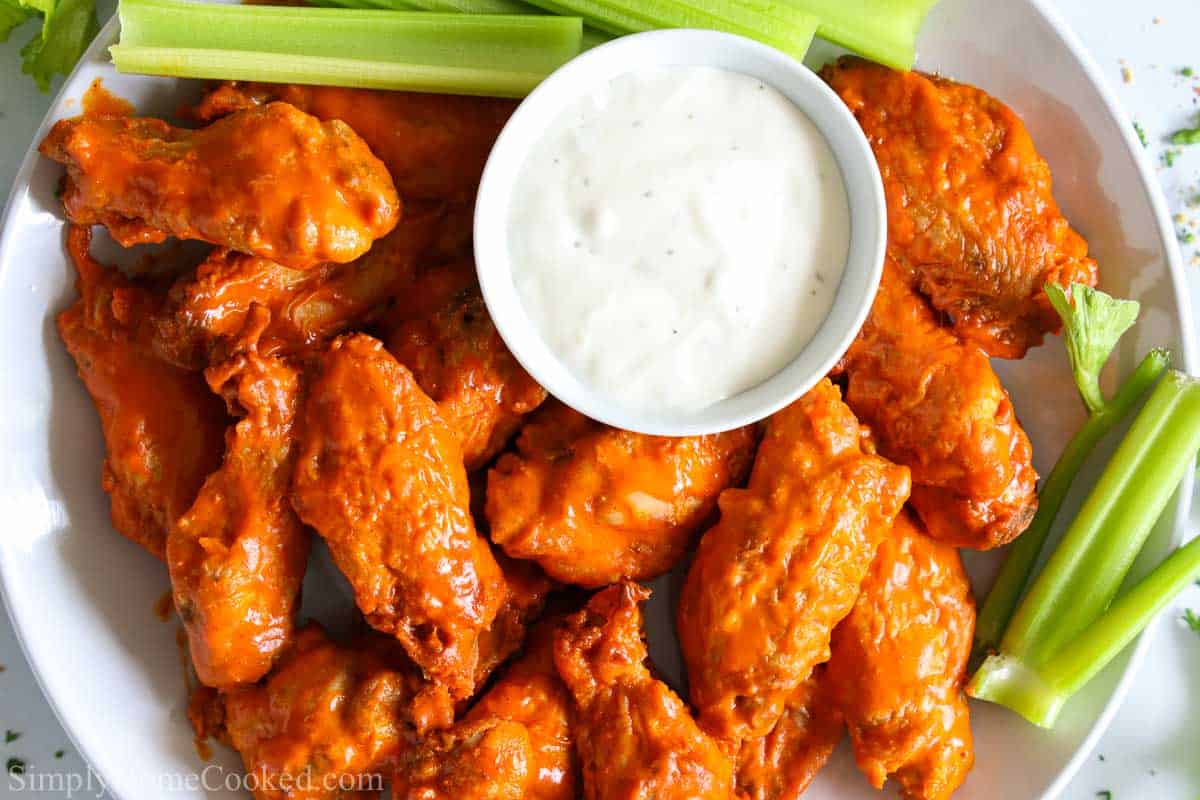overhead image of air fryer buffalo wings on with ranch and celery sticks beside them 