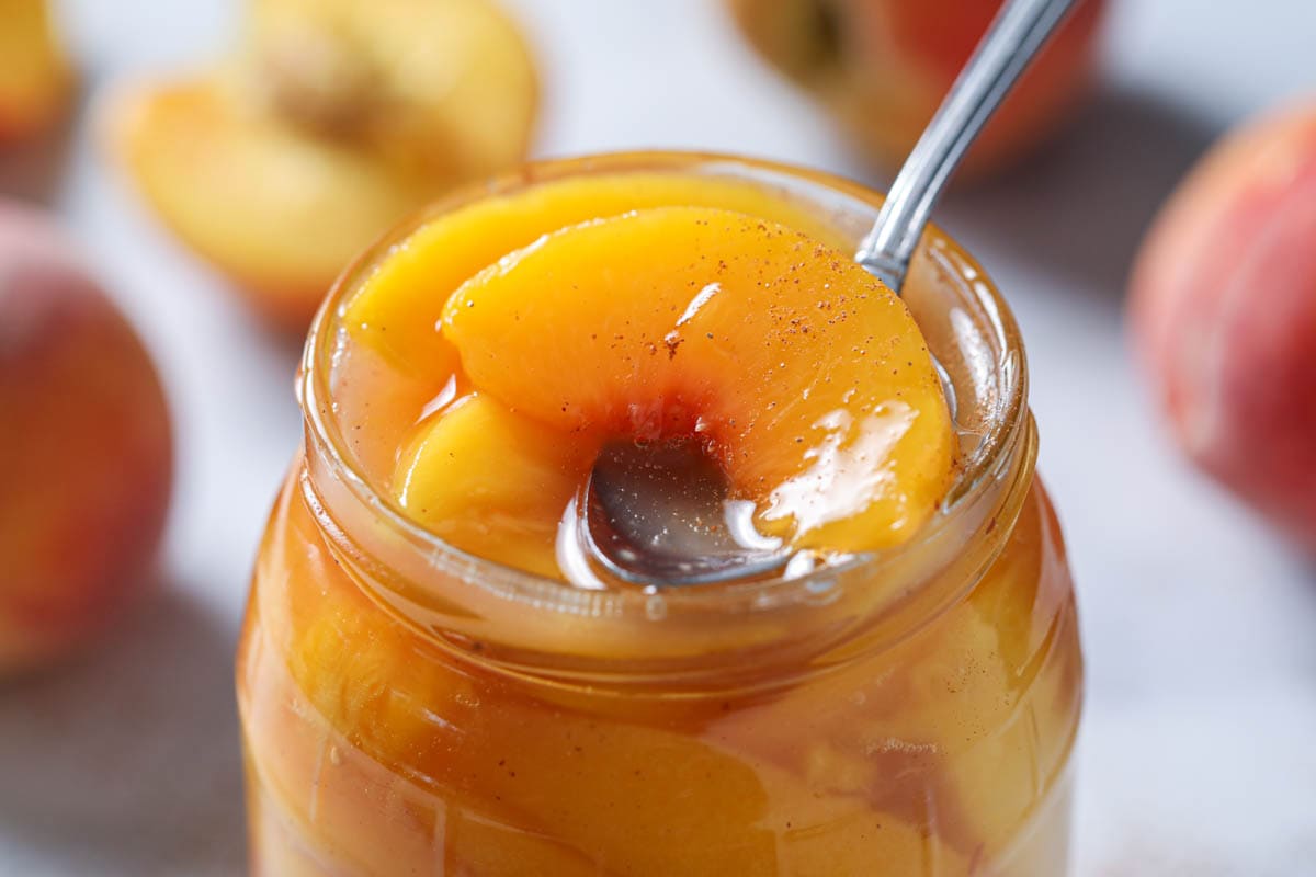 Peach Pie Filling in a mason jar with a spoon. 