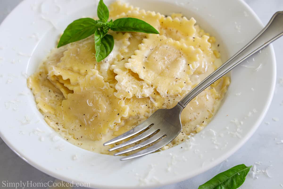 Plate of Easy Four Cheese Ravioli with herbs on top and a fork on the side of the plate.