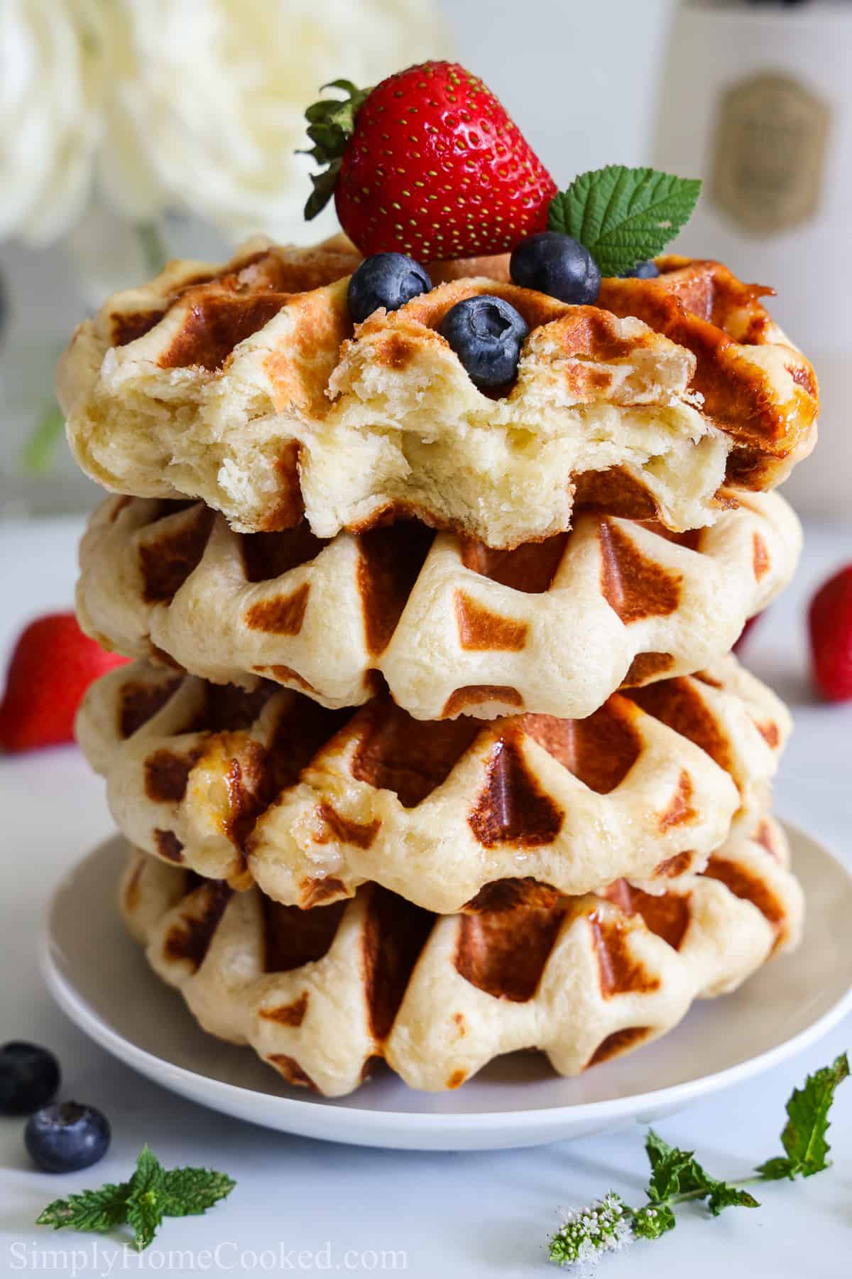 Stack of Belgian Liege Waffles topped with blueberries and a strawberry. 
