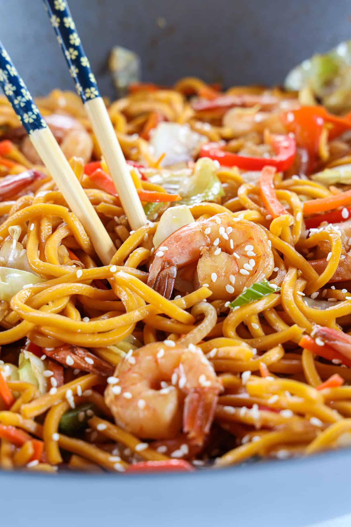 Cloe up of 30-Minute Shrimp Chow Mein with sesame seeds garnishing it and chopsticks in it.