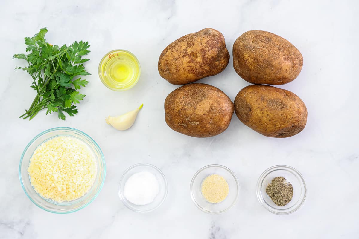 If you love fries, but not how unhealthy they are, then you have to try this recipe for Garlic Parmesan Potato Wedges. They use very little oil and are just as tasty and crispy as other potato wedges. #crispyairfryerpotatowedges #crispypotatowedges #crispygarlicparmesanpotatowedges #garlicparmesanpotatowedges Ingredients for Garlic Parmesan Potato Wedges, including russet potatoes, Parmesan cheese, avocado oil, garlic clove, onion powder, salt, pepper, and parsley, on a white background.