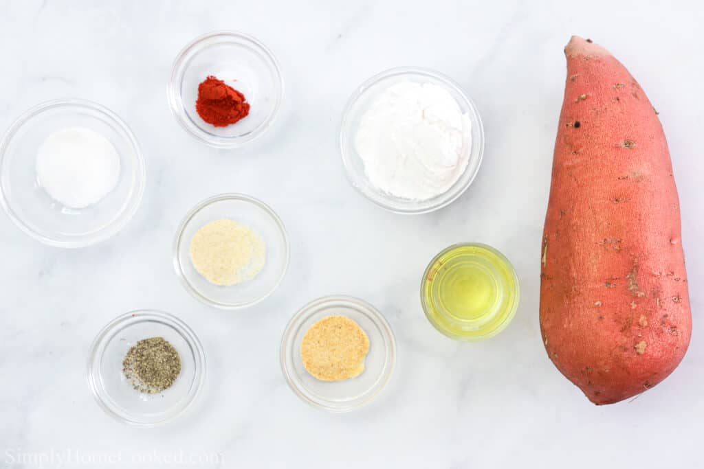 Ingredients for the BEST Air Fryer Sweet Potato Fries, including a sweet potato, salt, pepper, onion powder, garlic powder, paprika, oil, and tapioca starch, on a white background.