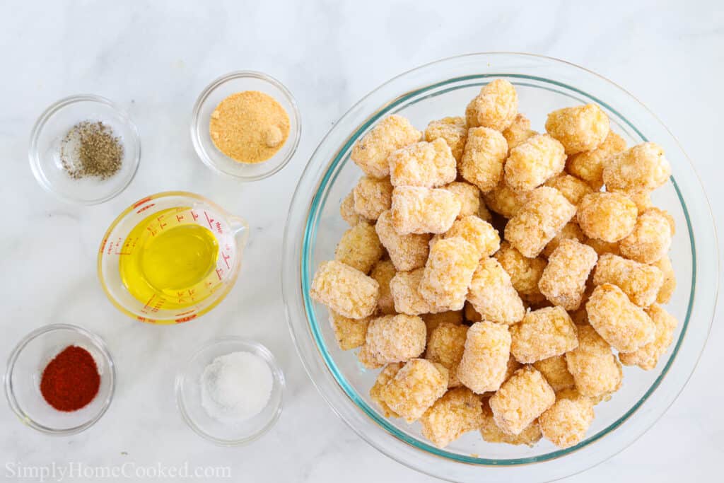 Ingredients for Crunchy Air Fryer Tater Tots, including tater tots, garlic powder, paprika, oil, salt, and pepper, on a white background.