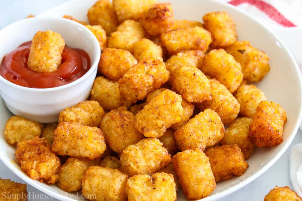 Plate of Crunchy Air Fryer Tater Tots with one in a small white bowl of ketchup.