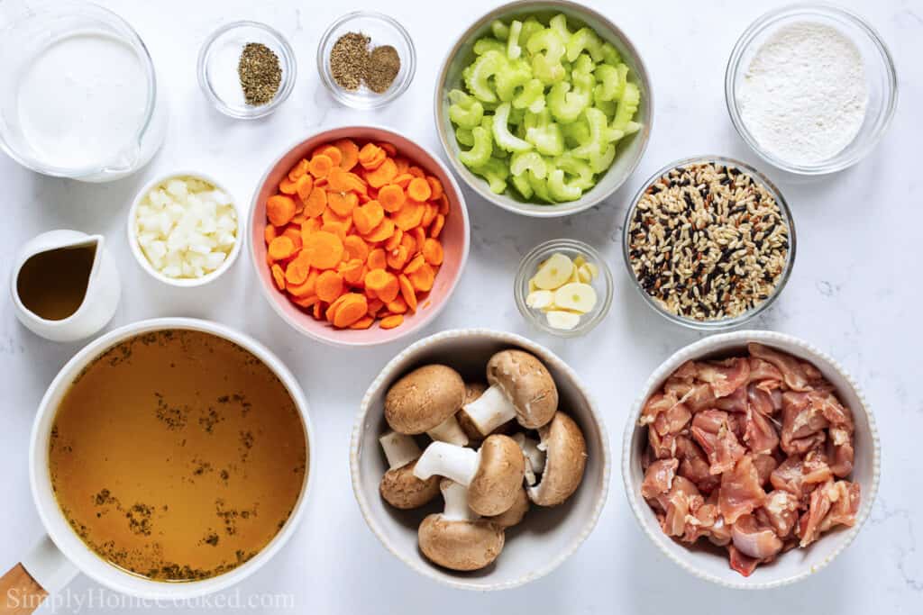Ingredients for Creamy Chicken and Wild Rice Soup, including chicken thighs, olive oil, chicken broth, heavy cream, flour, celery, carrots, garlic, mushrooms, onion, wild rice, salt, pepper, dried oregano, and thyme.